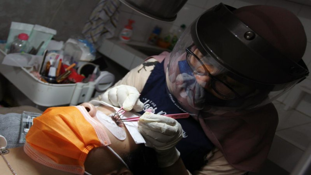 Arsip foto - Seorang ahli kecantikan dengan protokol kesehatan yang ketat tengah melakukan sambung bulu mata di Tangerang, Banten, Selasa (14/7/2020). (ANTARA FOTO/Muhammad Iqbal/hp)