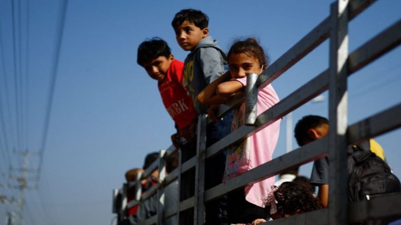Anak-anak menyaksikan warga Palestina melarikan diri dari Gaza utara, di tengah konflik yang sedang berlangsung antara Israel dan kelompok militan Palestina Hamas, di Jalur Gaza tengah, 9 November 2023. (Foto: Dok/Mohammed Salem/Reuters)