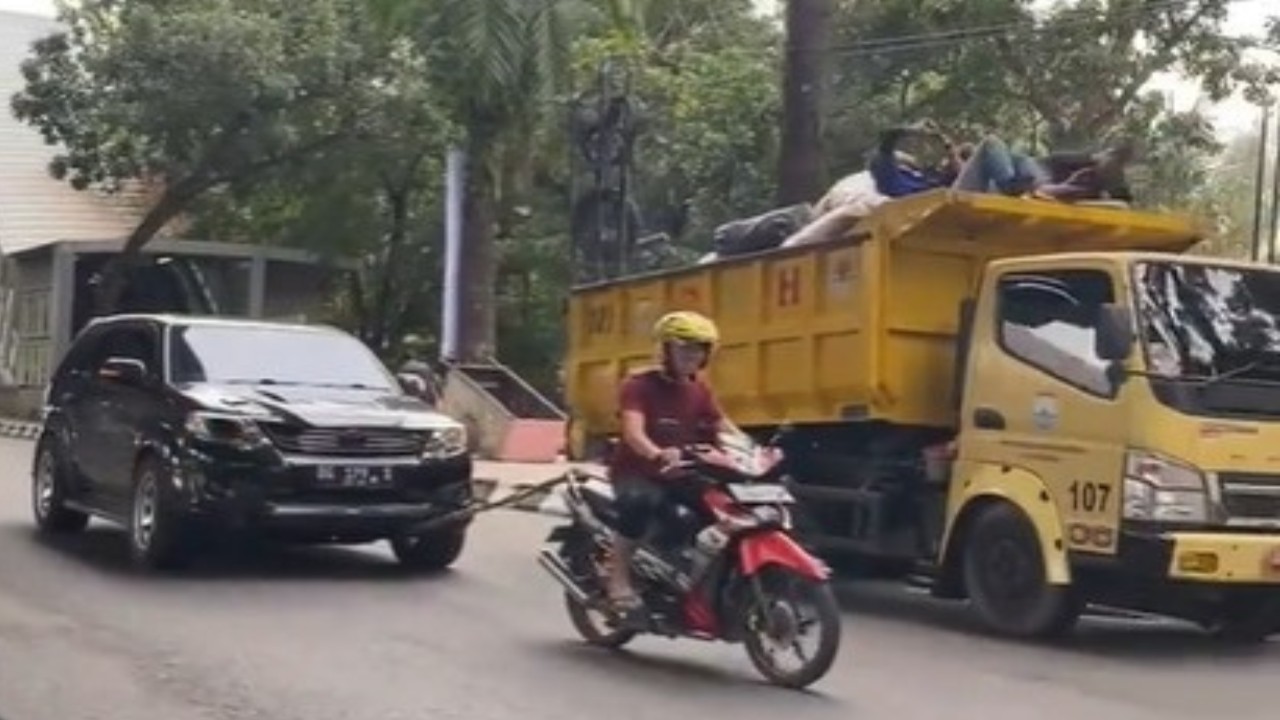 Seorang pengemudi motor Supra X menarik mobil yang mogok. (Tangkap layar)