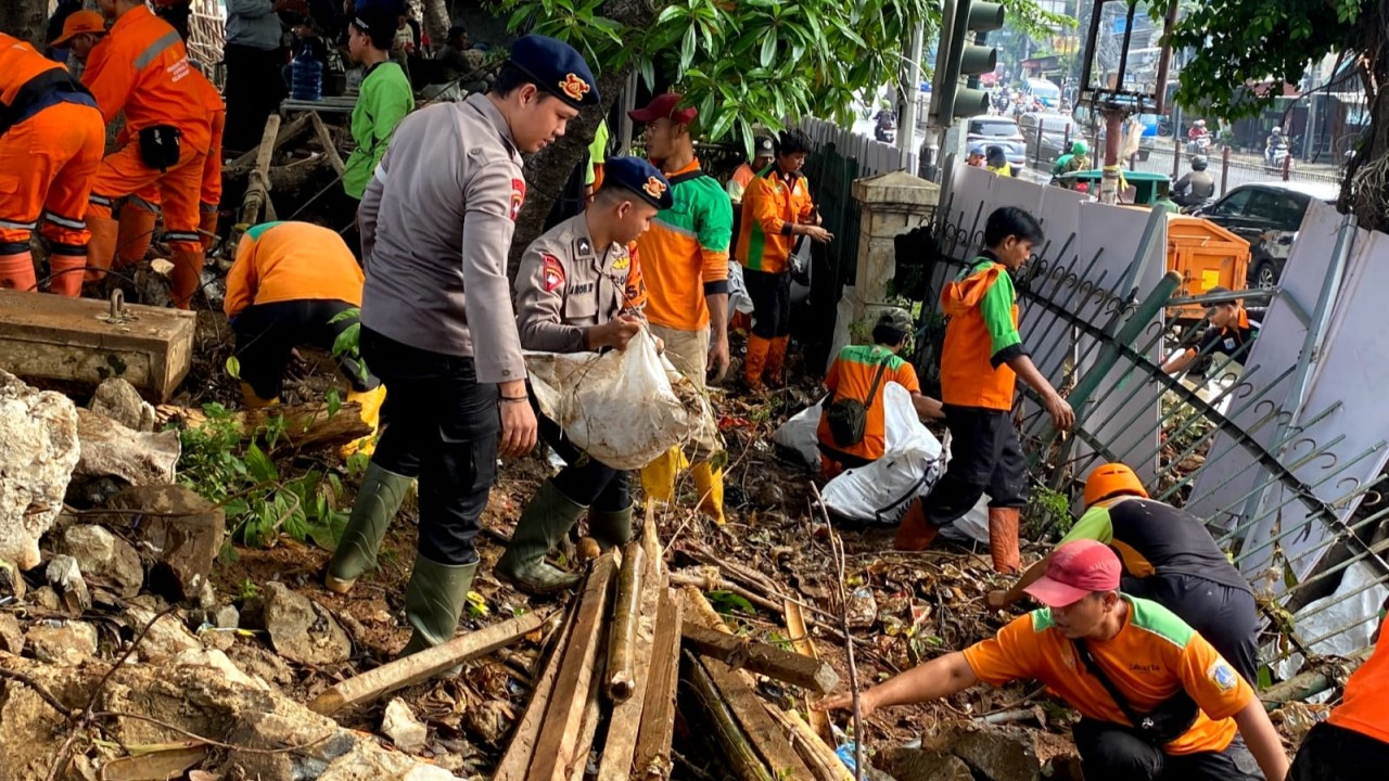 Polisi ikut bantu membersihkan sampah akibat dari tanggul kali Hek yang jebol.