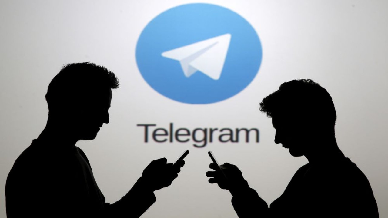 Dua pria berpose dengan ponsel pintar di depan layar yang memperlihatkan logo Telegram dalam ilustrasi gambar yang diambil di Zenica, Bosnia dan Herzegovina, pada 18 November 2015. (Foto: Dado Ruvic/Reuters)