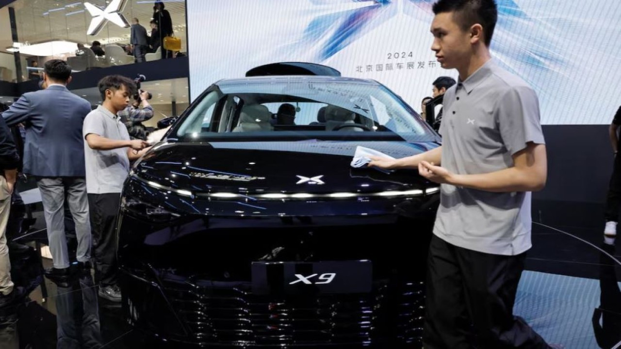 Anggota staf membersihkan kendaraan listrik Xpeng X9 yang dipajang di pameran otomotif Beijing Auto Showa 2024, di Beijing, China, 25 April 2024. (Foto: Dok/Tingshu Wang/Reuters)