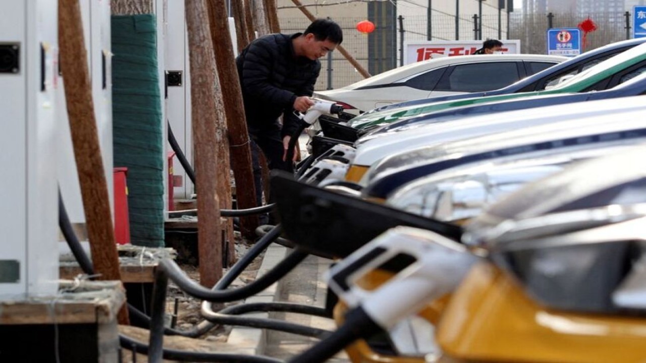 Seorang pria memegang steker pengisi daya untuk mengisi daya mobil di stasiun pengisian kendaraan listrik (EV) Smart Charge di Beijing, China, pada 2 Februari 2024. (Foto: Dok/Florence Lo/Reuters)