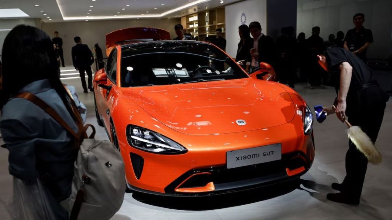 Seorang staf membersihkan kendaraan listrik Xiaomi SU7 yang dipajang di Beijing Auto Show 2024, pada 25 April 2024. (Foto: Tingshu Wang/Reuters)