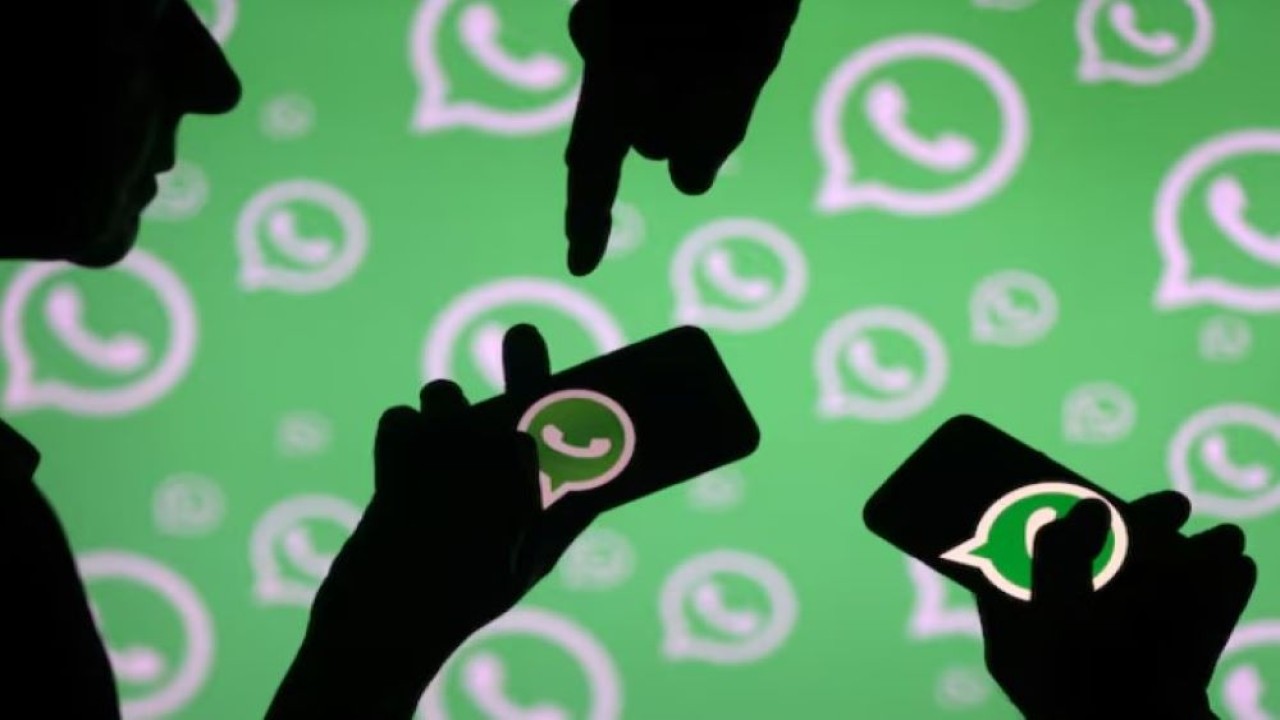 Pria berpose dengan smartphone di depan logo WhatsApp. (Foto: Dok/Dado Ruvic/Reuters)