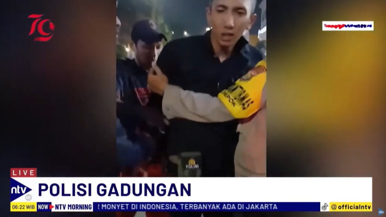 Seorang polisi gadungan dengan tangan terikat di kepung warga dan sejumlah pengendara yang melintas.