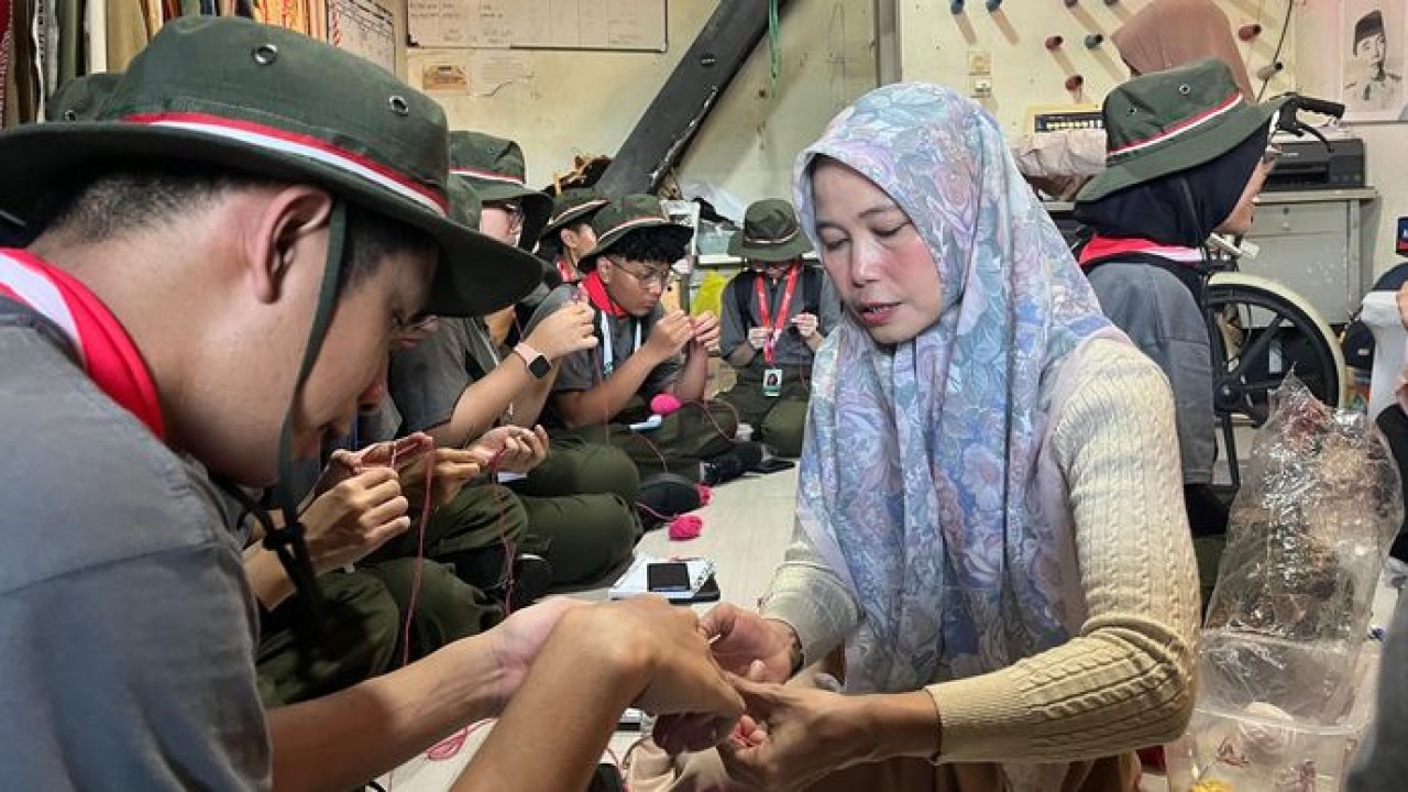 Penyandang disabilitas tuna daksa sekaligus perajut kain, Elis Juarsih (47) mengajarkan cara membuat gelang dengan merajut benang kepada anggota Green Warriors diacara Green Bus Pertamina 2026, rabu (8/7) di Kampoeng Radjoet Binong. (Pertamina)